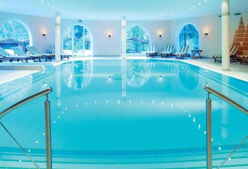 a large swimming pool with blue water in a building at Waldhotel Doldenhorn in Kandersteg