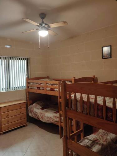 a bedroom with two bunk beds and a ceiling fan at Minute walk to the beach in Munxar