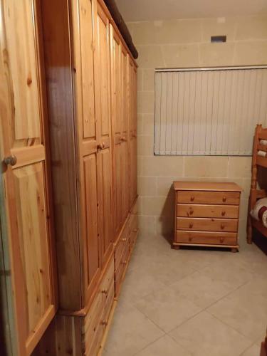 a bedroom with wooden cabinets and a wooden dresser at Minute walk to the beach in Munxar