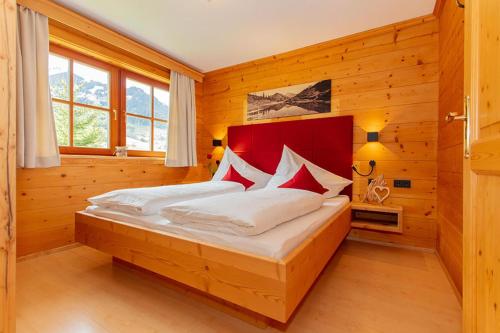 a bedroom with a large bed with a red headboard at Blockhaus Ganschitter in Grossarl