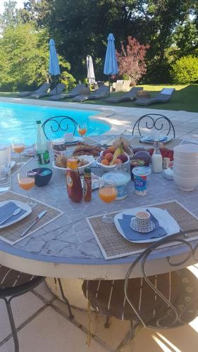 - une table avec de la nourriture et des boissons à côté de la piscine dans l'établissement Gite De Merugat, à Valeilles