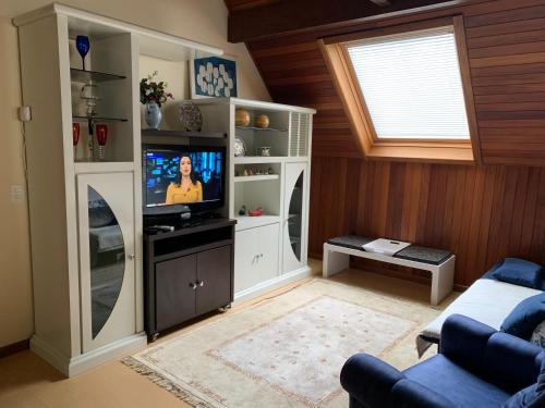 - un salon avec une télévision dans un meuble blanc dans l'établissement Apartamento Castelinho - Centro, à Gramado