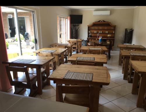 uma sala de aula com mesas e cadeiras de madeira num quarto em Rock Art Guesthouse em Witbank