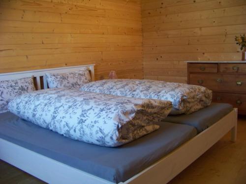 a bedroom with two beds and a wooden wall at Ferienhaus Brunnenweiher in Kißlegg