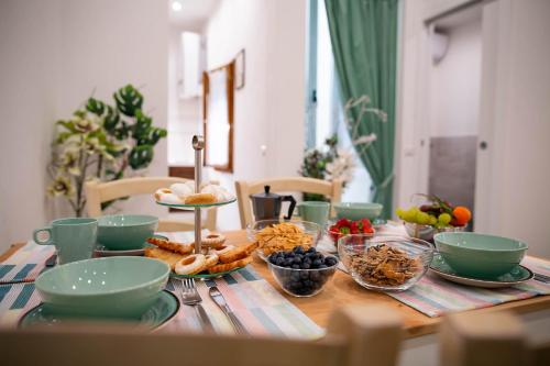 einem Holztisch mit Schalen und Teller mit Lebensmitteln darauf in der Unterkunft Novella Benedicta Apartments in Florenz