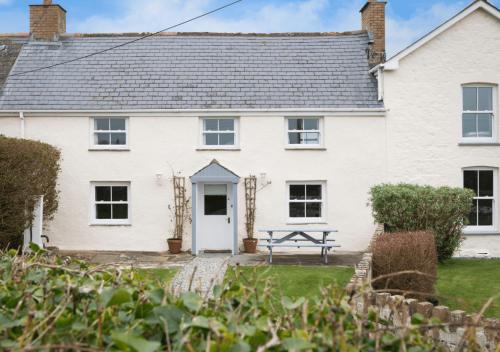 a white house with a picnic table in front of it at Bejowan Cornish Cottage in Newquay