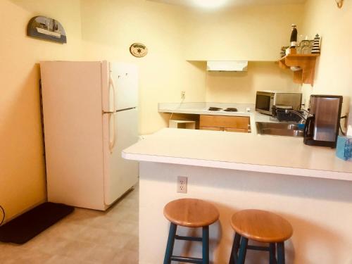 a kitchen with two stools and a white refrigerator at Driftwood Inn in Homer