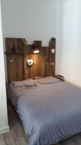 een slaapkamer met een bed met een houten hoofdeinde bij La comédie in Lons-le-Saunier