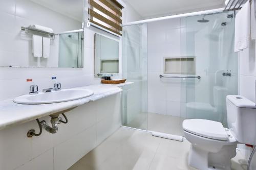 a bathroom with a toilet sink and a shower at Wyndham Golden Foz Suítes in Foz do Iguaçu