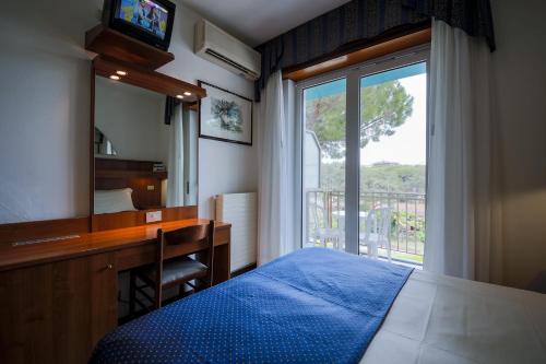 a bedroom with a bed and a desk and a mirror at Hotel Vina De Mar in Lignano Sabbiadoro