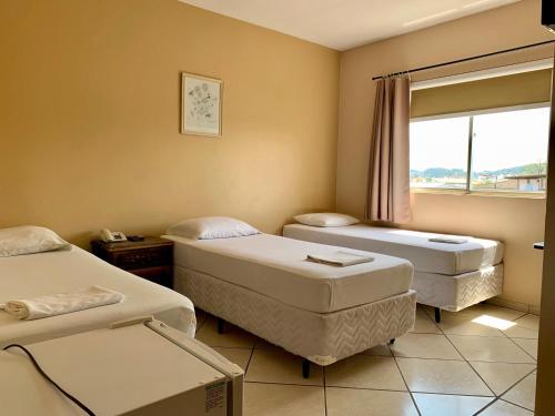 a hospital room with two beds and a window at Hotel Pontal in Palhoça