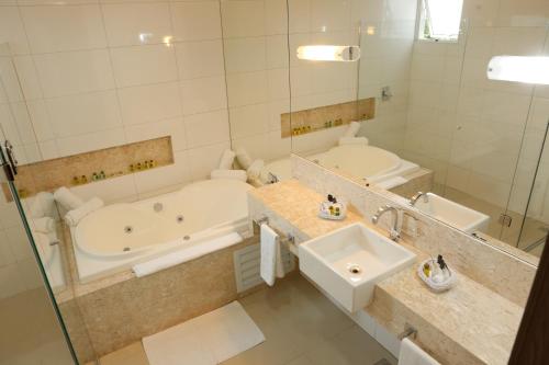 Baño blanco con bañera y lavamanos en Agulhon Hotel en Primavera do Leste