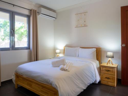 ein Schlafzimmer mit einem Bett mit weißen Laken und einem Fenster in der Unterkunft Sirena Resort Curaçao in Willemstad