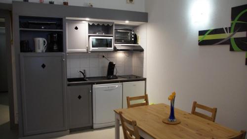 uma cozinha com uma mesa e uma pequena cozinha com um micro-ondas em Appartement 4 personnes Saint-Lary Village em Saint-Lary-Soulan