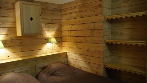 Un dormitorio con una pared de madera y una cama. en Appartement 4 personnes Saint-Lary Village, en Saint-Lary-Soulan