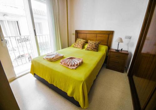 1 dormitorio con 1 cama con sábanas amarillas y ventana en Santa Faz Old Town, en Benidorm