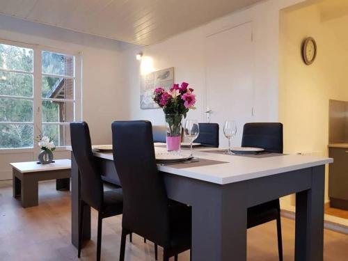 a dining room table with chairs and a vase of flowers at Cottage du lac de Chaumeçon avec étang privé in Brassy