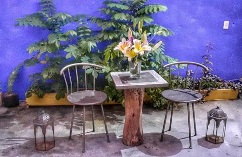 a table with two chairs and a vase with flowers at Lola Atlachinolli in Sayulita