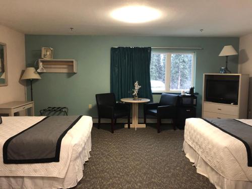 Aurora Denali Lodge في هيلي: غرفة فندقية بسريرين وطاولة وتلفزيون