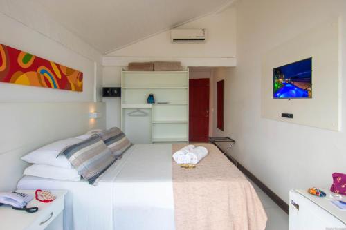 a small bedroom with a bed and a desk at Chez Pitu Praia Hotel in Búzios