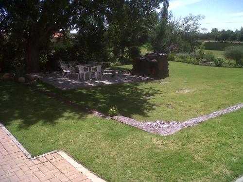 a backyard with a table and chairs in the grass at The Guest House Standerton in Standerton