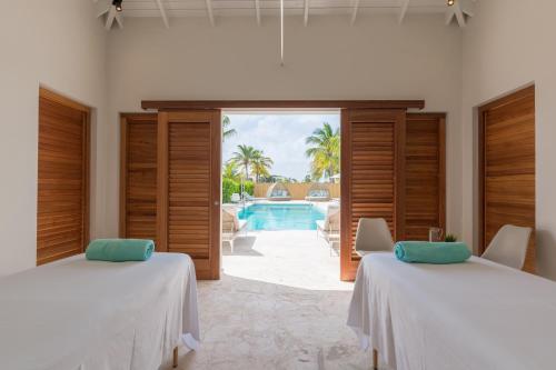 twee bedden in een kamer met uitzicht op het zwembad bij Dolphin Suites & Wellness Curacao in Willemstad