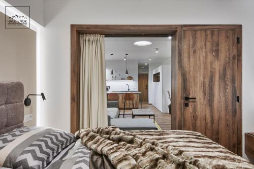 a bedroom with a bed and a living room at HREBIENOK MOUNTAIN APARTMENTS STARÝ SMOKOVEC in Smokovce