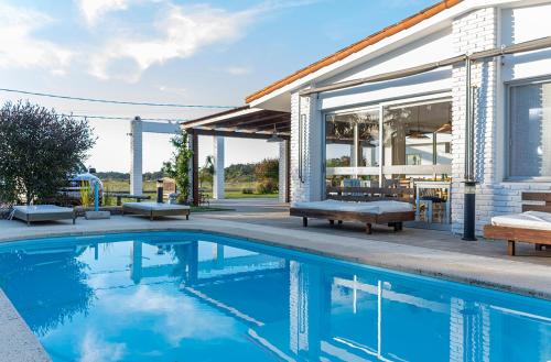 a swimming pool with benches next to a house at Aparthotel la Música y el Mar in Maldonado