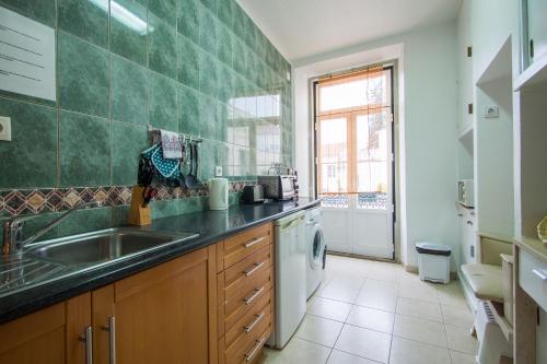 a green tiled kitchen with a sink and a window at #DuplexduBocage com vista lateral para a Praça in Setúbal