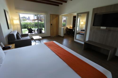 a bedroom with a large bed and a living room at Casa Andina Standard Chincha in Chincha Alta