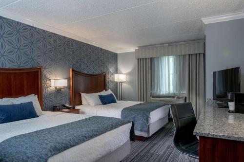 a hotel room with two beds and a flat screen tv at Best Western PLUS Franklin Square Inn in Troy