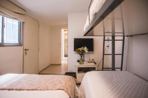 2 Betten in einem Zimmer mit einem TV und einem Schlafzimmer in der Unterkunft LA PORTEÑA in Buenos Aires