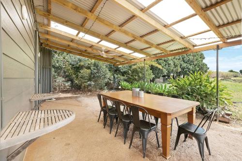 a patio with a wooden table and chairs and a bench at Farm & Co-sy by Kingscliff Accommodation in Cudgen