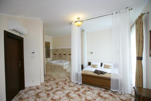 a bedroom with a bed and a tub in a room at Hotel Atena Wedding, Business & Spa in Ciechanów