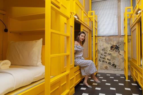 a woman is sitting in a yellow bunk bed at Azure Hostel Bangkok in Bangkok