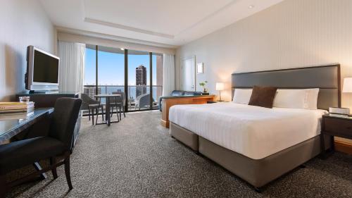 ゴールドコーストにあるOaks Gold Coast Hotelのベッド、デスク、テレビが備わるホテルルームです。
