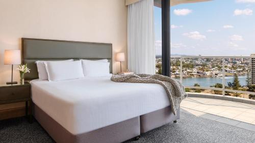 a bedroom with a large bed and a large window at Oaks Gold Coast Hotel in Gold Coast
