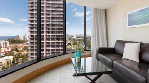 a living room with a couch and large windows at Oaks Gold Coast Hotel in Gold Coast