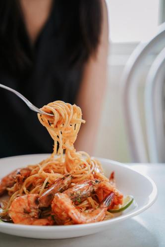 a plate of pasta with shrimp on a fork at Azure Hostel Bangkok in Bangkok