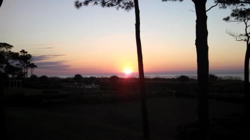 a sunset with the sun setting in the distance at Nothing But Ocean in Forest Beach in Hilton Head Island