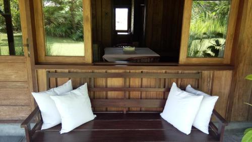 a room with white pillows on a bench with a window at Gardenia Country Inn in Tomohon