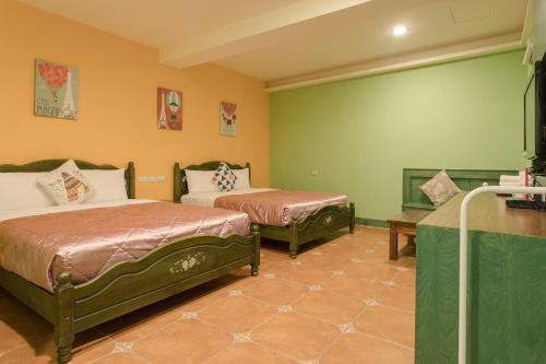 two beds in a room with green walls at 墾丁海園別館Hai Yuan Inn in Kenting