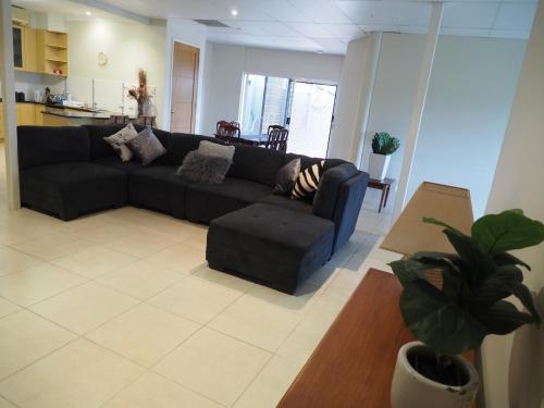 a living room with a black couch and a kitchen at Accommodation on Westlake Mount Ommaney in Mount Ommaney