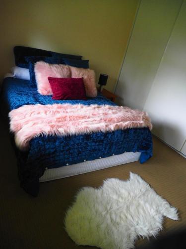 a bedroom with a bed with two pillows and a white rug at Accommodation on Westlake Mount Ommaney in Mount Ommaney