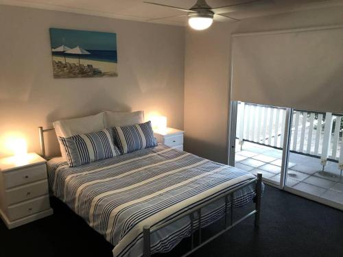 a bedroom with a bed with two lamps and a balcony at Moontana in Port Moonta