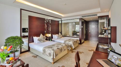 a hotel room with two beds and a desk at Brilliant Hotel - Afternoon Tea Inclusive in Da Nang
