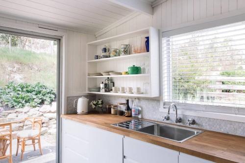 a kitchen with white cabinets and a sink and a window at Ellerslie Cottage in Metcalfe
