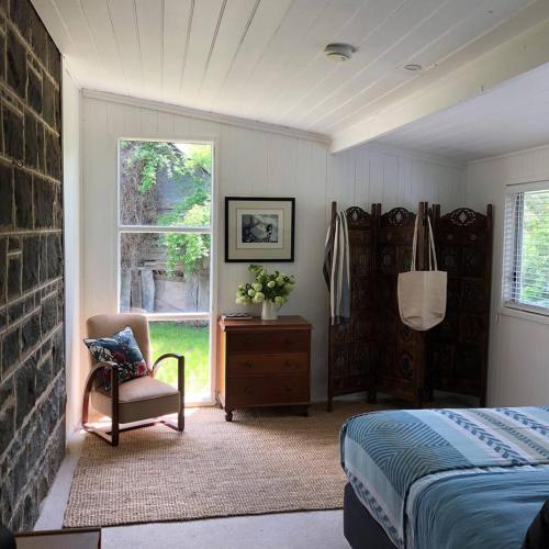a bedroom with a bed and a chair and a window at Ellerslie Cottage in Metcalfe