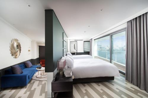 um quarto com uma cama grande e um sofá azul em Hotel Marinabay Seoul em Gimpo