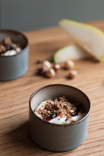 Domaine les Bruyères في Gambais: وعاء من الزبادي مع المكسرات على طاولة خشبية